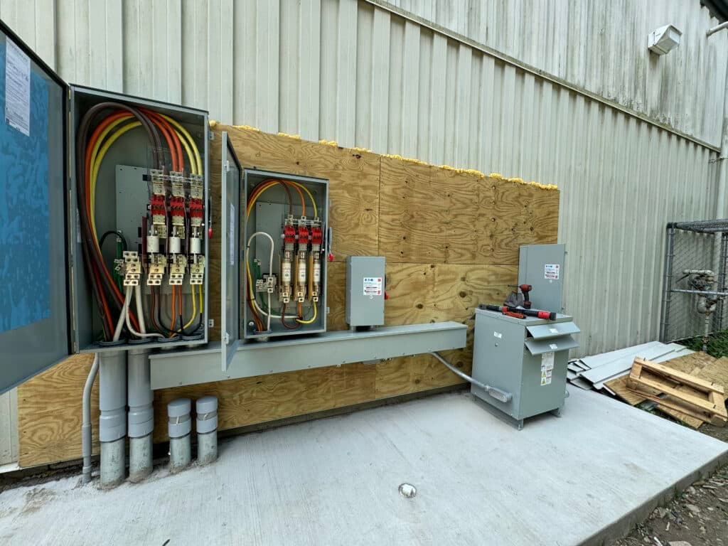 Electrical panel and circuit breakers mounted on a wall with organized wiring and safety features.