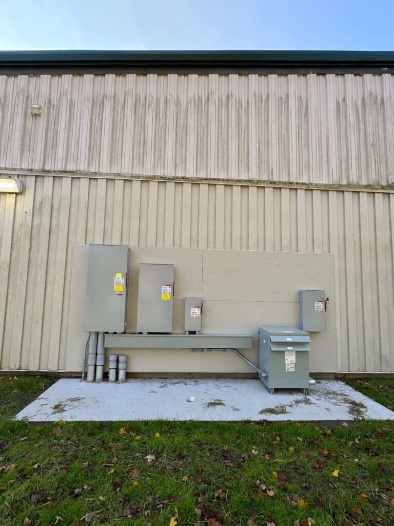 Electrical equipment installation on exterior wall with conduit and utility box.