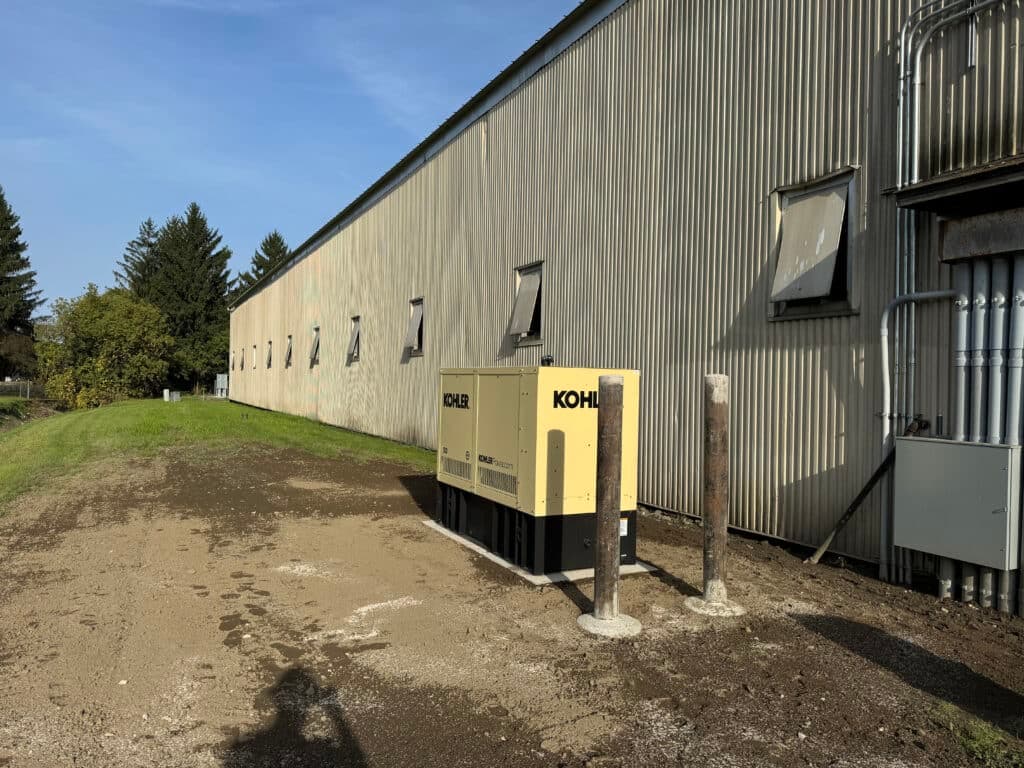 Kohler generator outside a commercial building with green landscape and trees.