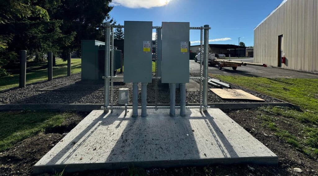 Electrical distribution boxes on a concrete pad in an outdoor industrial setting.
