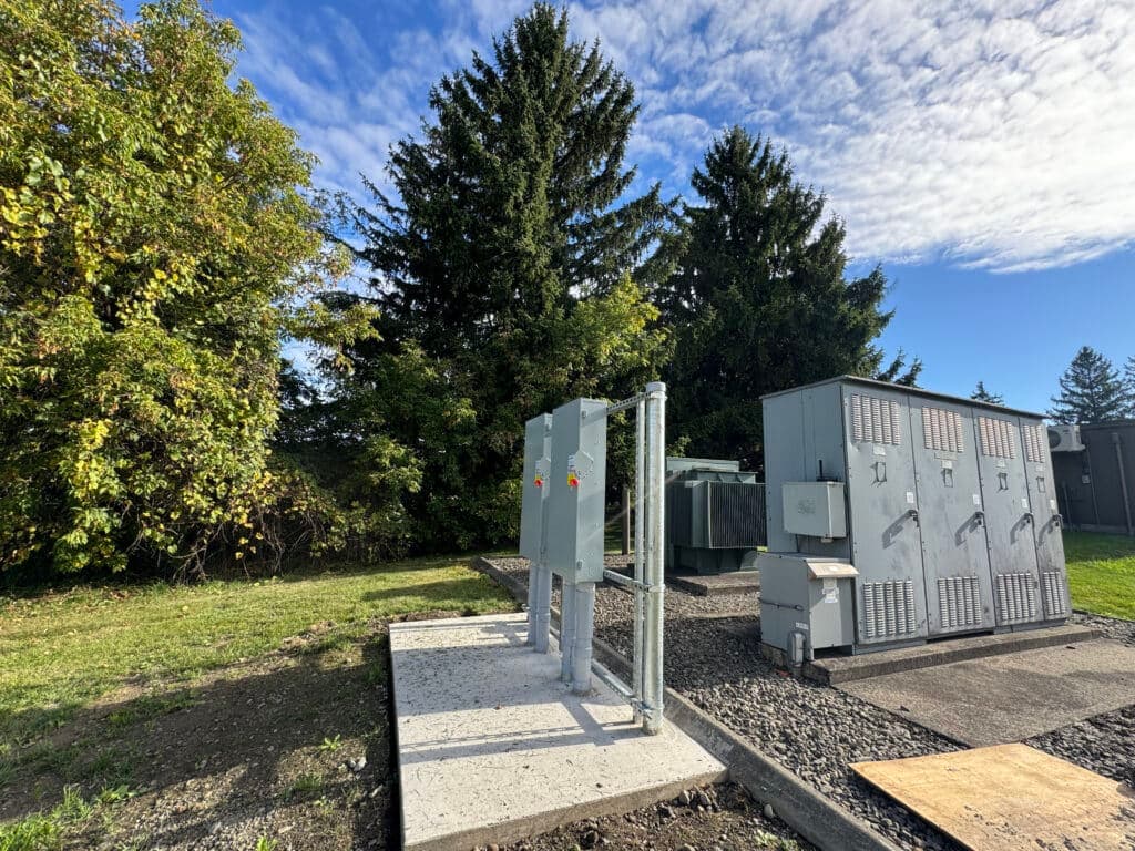 Utility equipment installation in a grassy area with trees and blue sky.