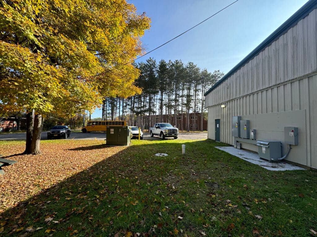 Autumn scene featuring buildings and trees, with parked vehicles and scattered leaves.