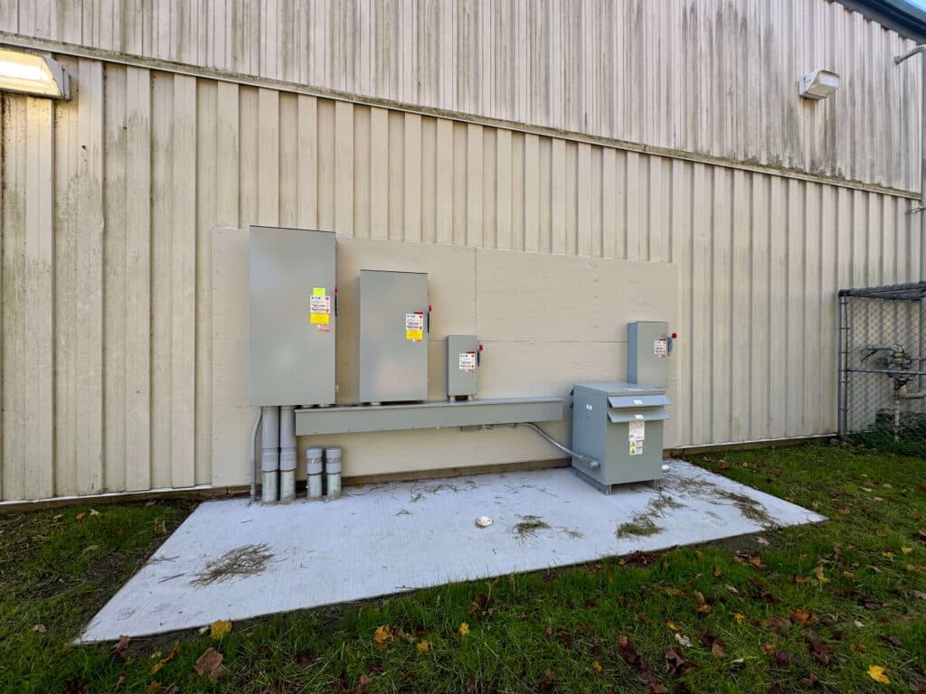 Electrical service equipment mounted on exterior wall of industrial building.